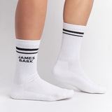 White mid-calf socks with two black stripes at the top and the text 'JAMES BARK' in black on the ankle, shown worn on a person’s feet.