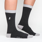 Black and gray striped mid-calf socks with a solid gray cuff, heel, and toe, featuring a small dog graphic near the ankle and the text 'JAMES BARK' near the toe, shown worn on a person’s feet.