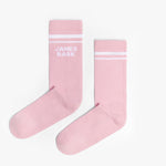 A pair of pink mid-calf socks with two white stripes at the top and the text 'JAMES BARK' printed in white near the ankle. The socks are laid flat on a white surface