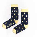 A pair of navy blue mid-calf socks with a yellow cuff, heel, and toe, featuring a pattern of lemons and the text 'JAMES BARK' printed in yellow near the toe. The socks are laid flat on a white surface.