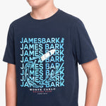 A navy blue short-sleeve T-shirt with a light blue and white graphic print featuring the text 'JAMES BARK' repeated, a sailboat, and 'MONTE CARLO SAILING CLUB SINCE 1915'