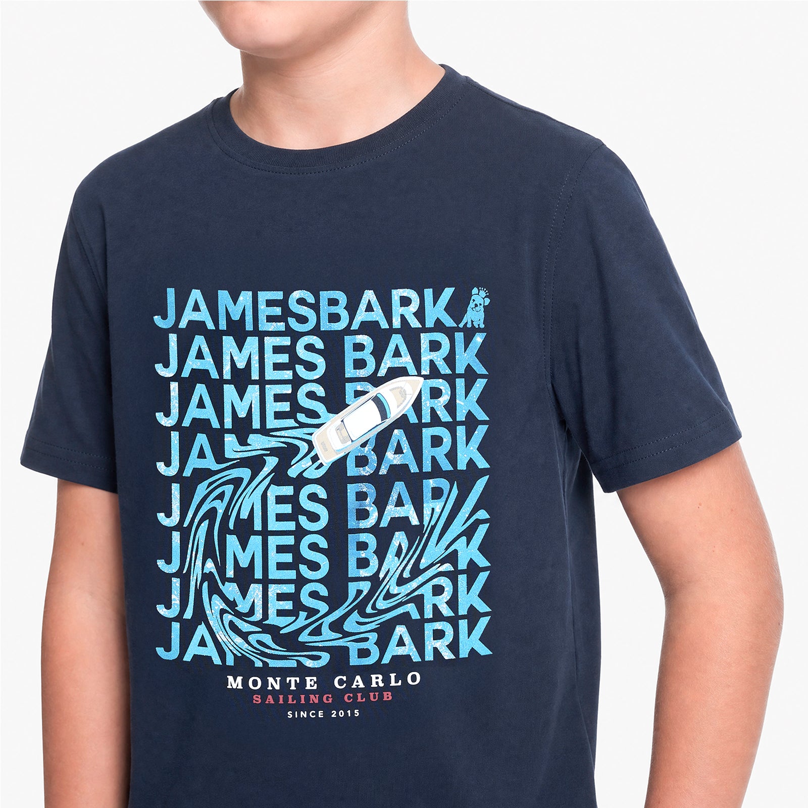 A navy blue short-sleeve T-shirt with a light blue and white graphic print featuring the text 'JAMES BARK' repeated, a sailboat, and 'MONTE CARLO SAILING CLUB SINCE 1915'