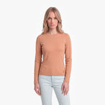 Woman wearing a tan long-sleeve shirt and light blue jeans on a white background