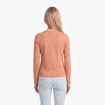 Woman wearing a brown long-sleeve top and light blue jeans on a white background