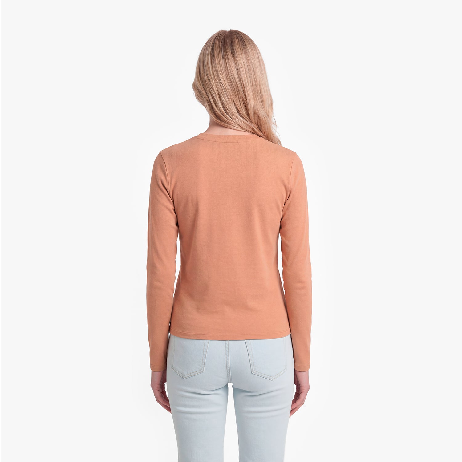 Woman wearing a brown long-sleeve top and light blue jeans on a white background