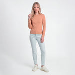 Woman wearing a brown sweater and light blue jeans on a white background