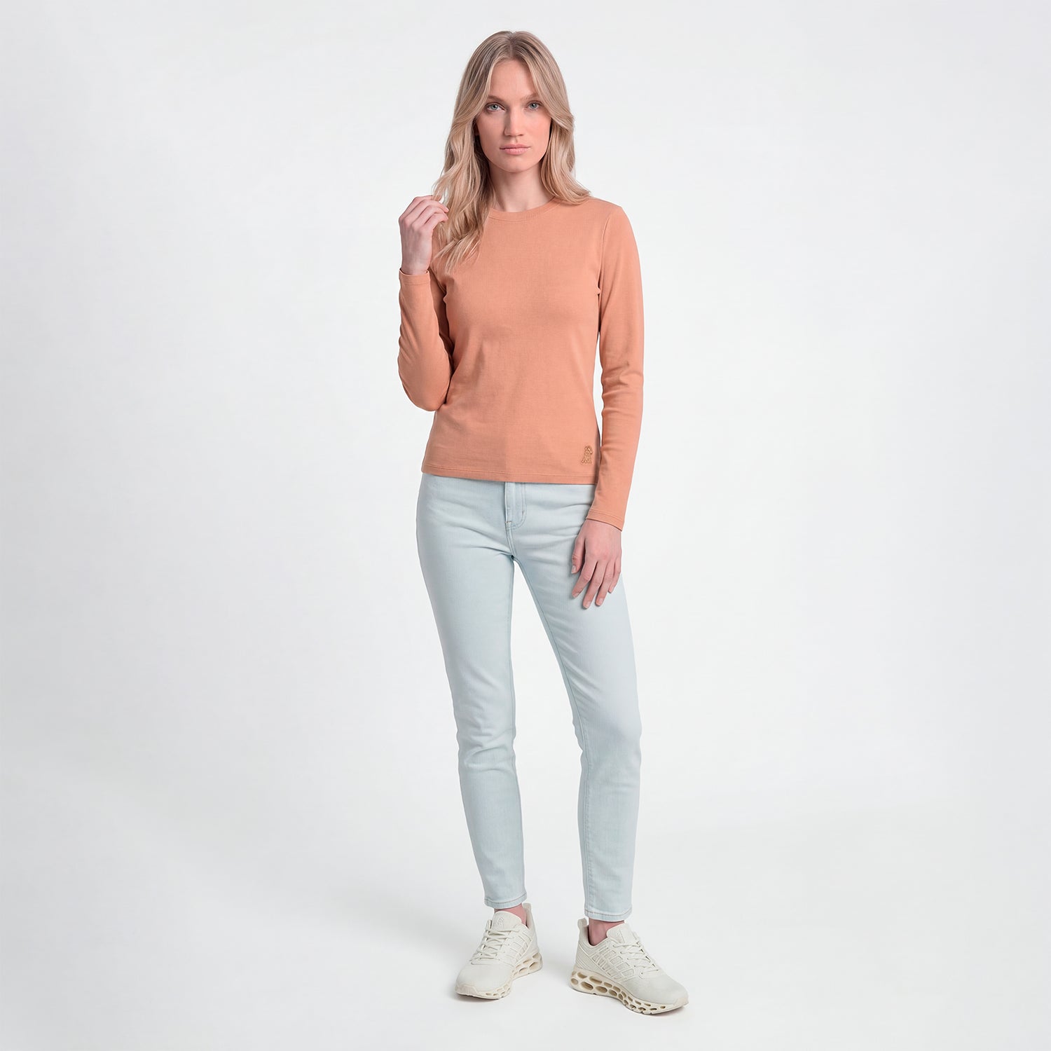Woman wearing a brown sweater and light blue jeans on a white background