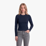 Woman wearing a navy long-sleeve top and gray jeans on a white background