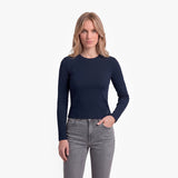 Woman wearing a navy long-sleeve top and gray jeans on a white background