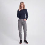 Woman wearing a navy long-sleeve top and gray jeans on a white background