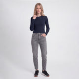 Woman wearing a navy long-sleeve top and gray jeans on a white background