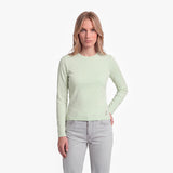 Woman wearing a light green long-sleeve shirt and light gray jeans on a white background