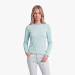 Woman wearing a light blue long-sleeve shirt and white pants on a white background