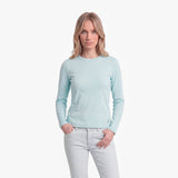 Woman wearing a light blue long-sleeve shirt and white pants on a white background