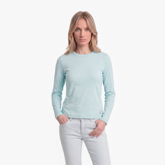 Woman wearing a light blue long-sleeve shirt and white pants on a white background