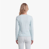 Woman wearing a light blue sweater and white pants on a white background
