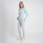 Woman wearing a light blue long-sleeve top and light gray jeans on a white background