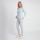 Woman wearing a light blue long-sleeve top and light gray jeans on a white background