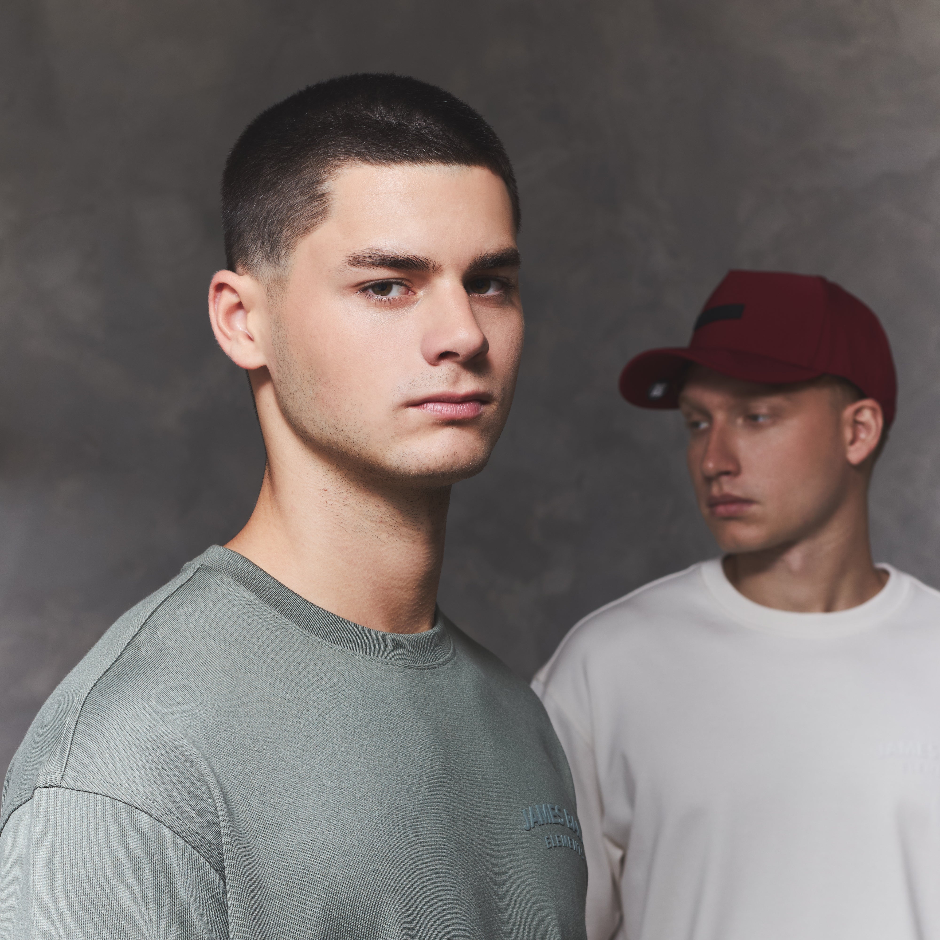 Two men standing side by side against a gray background