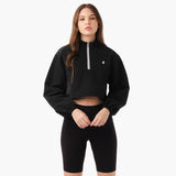 A model wearing a cropped jacket in a black color, styled with sporty shorts. The jacket has a relaxed fit , showcasing a casual look. The model stands in a confident pose against a neutral background.