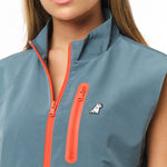 The image is a close-up of a woman wearing a fitted vest jacket. The jacket features a sleek design and is styled over a top. The background is a soft, neutral color that emphasizes the details of the vest.