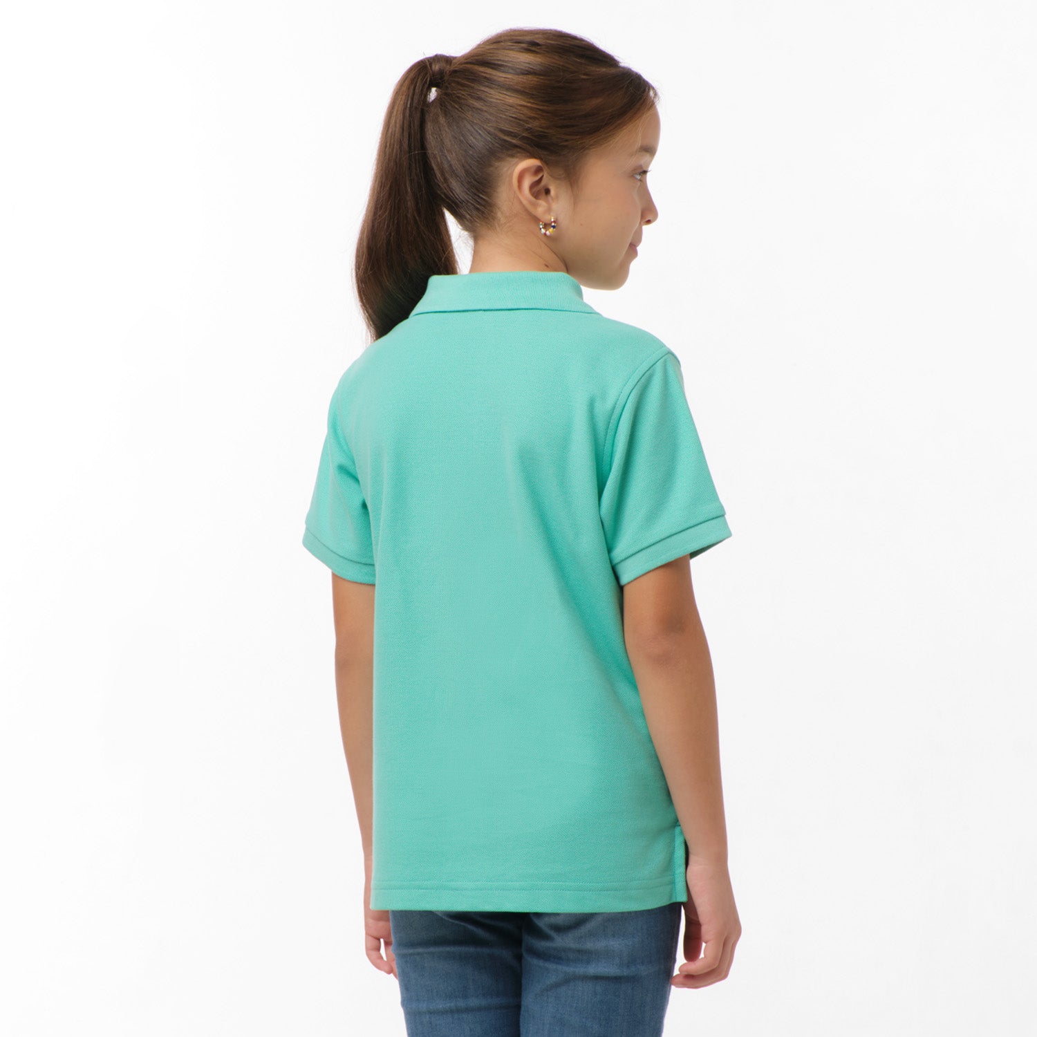 Rear view of the girl wearing the mint green polo shirt, showing the plain back design, paired with blue jeans.