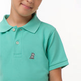 Close-up of the chest area of the mint green polo shirt, featuring the small embroidered logo.