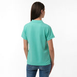 Rear view of the woman wearing the mint green polo shirt, showing the plain back design, paired with blue jeans.