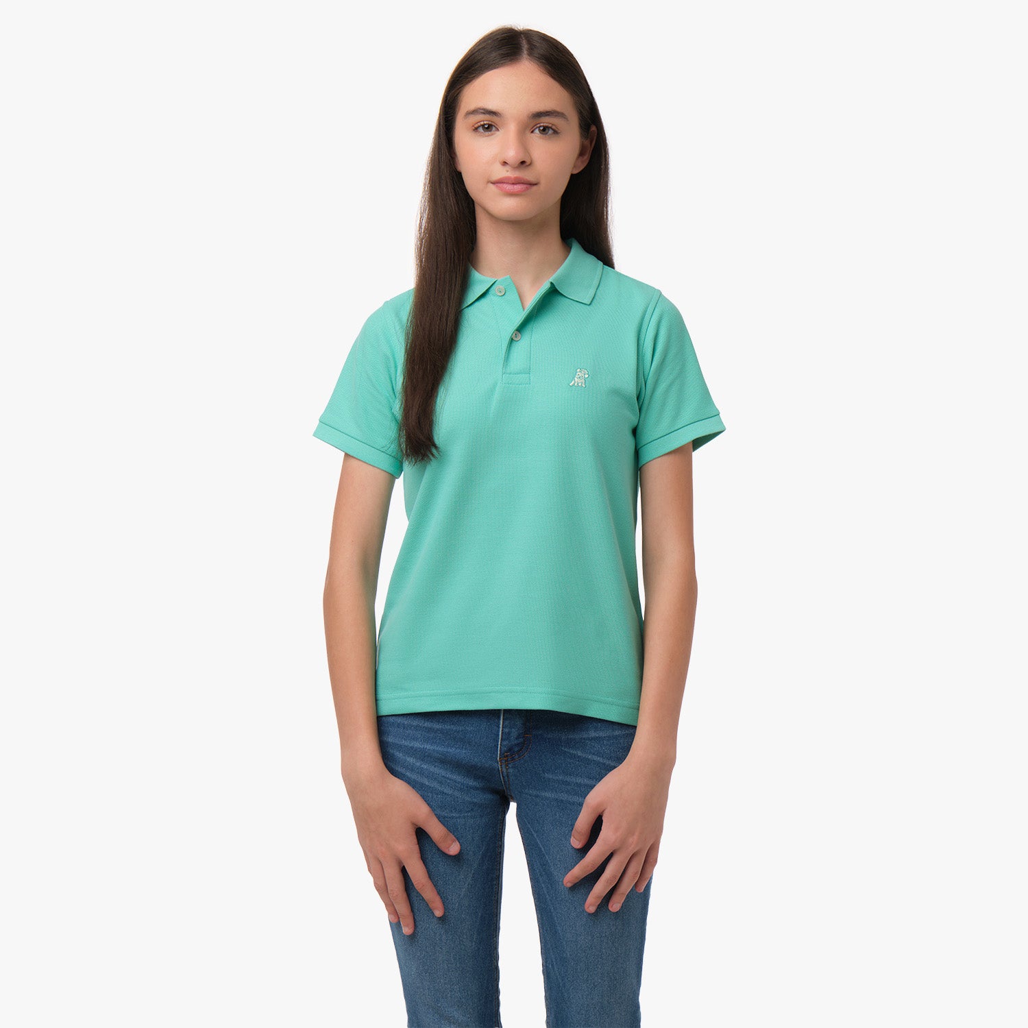 A young woman wearing a mint green polo shirt with a small embroidered logo on the chest, paired with blue jeans, standing with her hands at her sides.