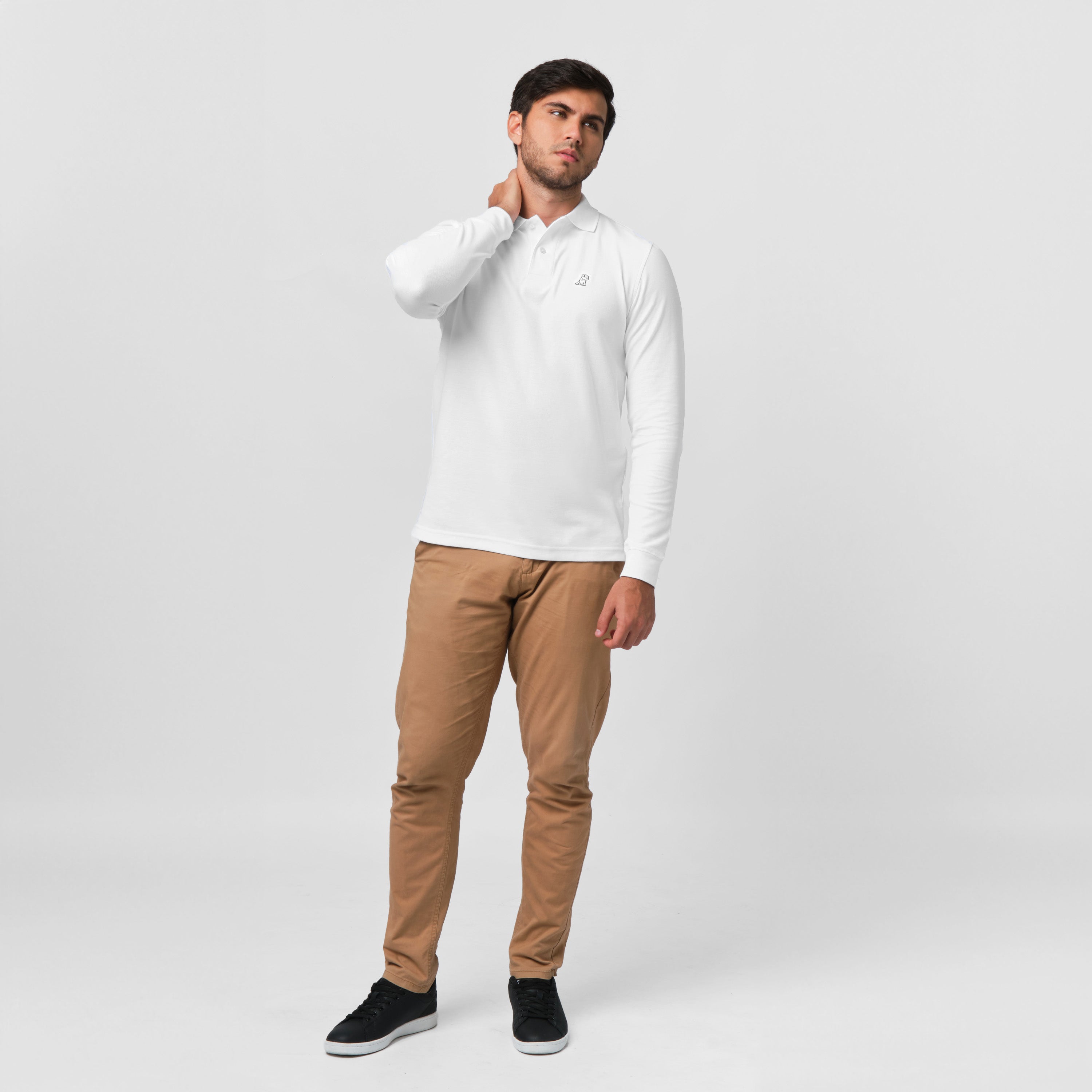 A full-body shot of the man wearing the white long-sleeved polo shirt and beige pants, standing casually.