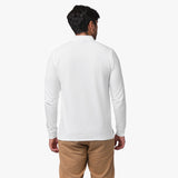 A back view of the man wearing the white long-sleeved polo shirt and beige pants, showing the fit from behind.