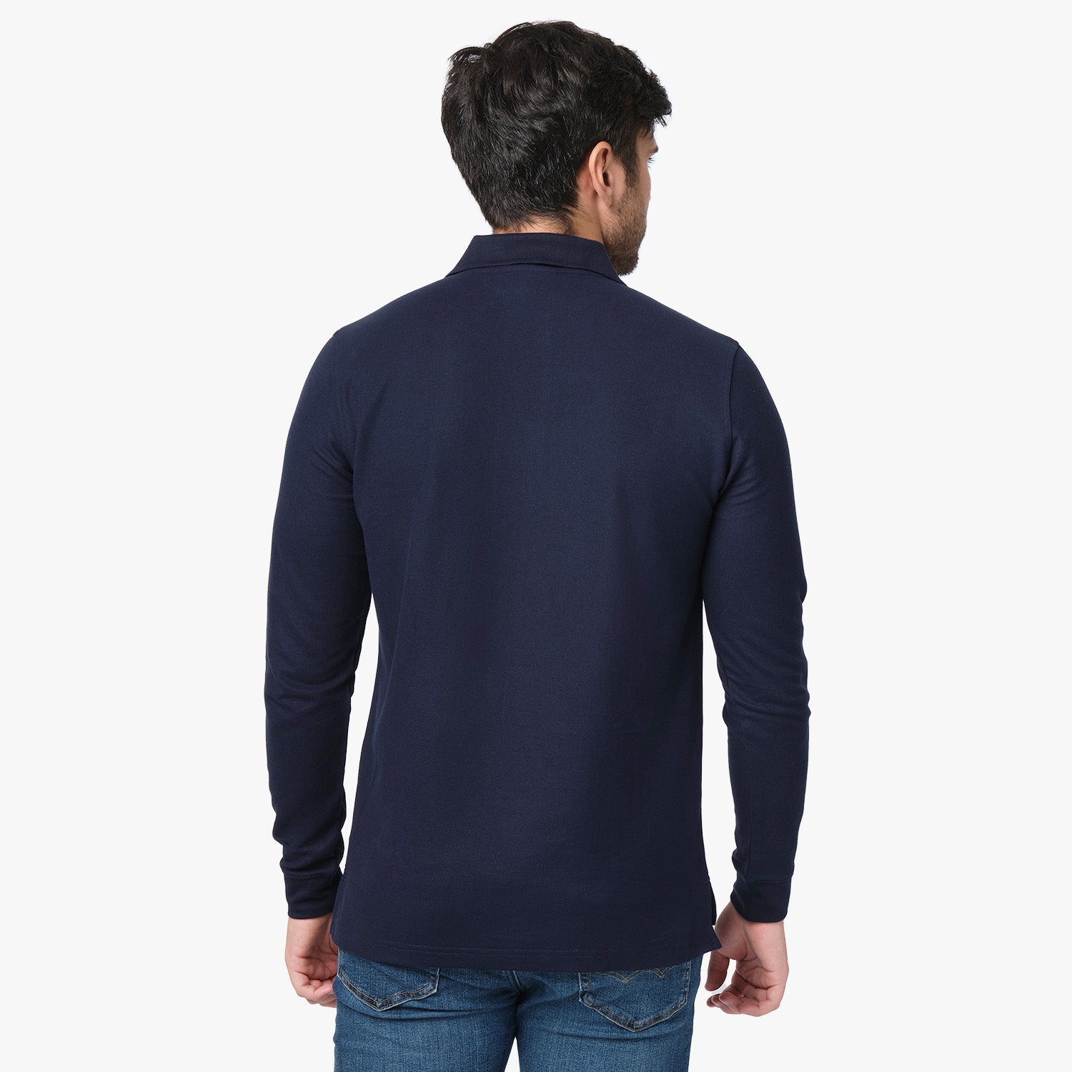 A back view of the man wearing the navy blue long-sleeved polo shirt and blue jeans, showing the fit from behind.