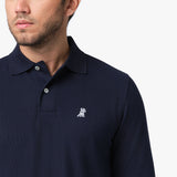 A close-up of the chest area of the navy blue polo shirt, highlighting the small embroidered logo and part of the collar.