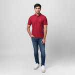 A red polo shirt laid flat, showing the collar and small golden embroidered logo on the chest.