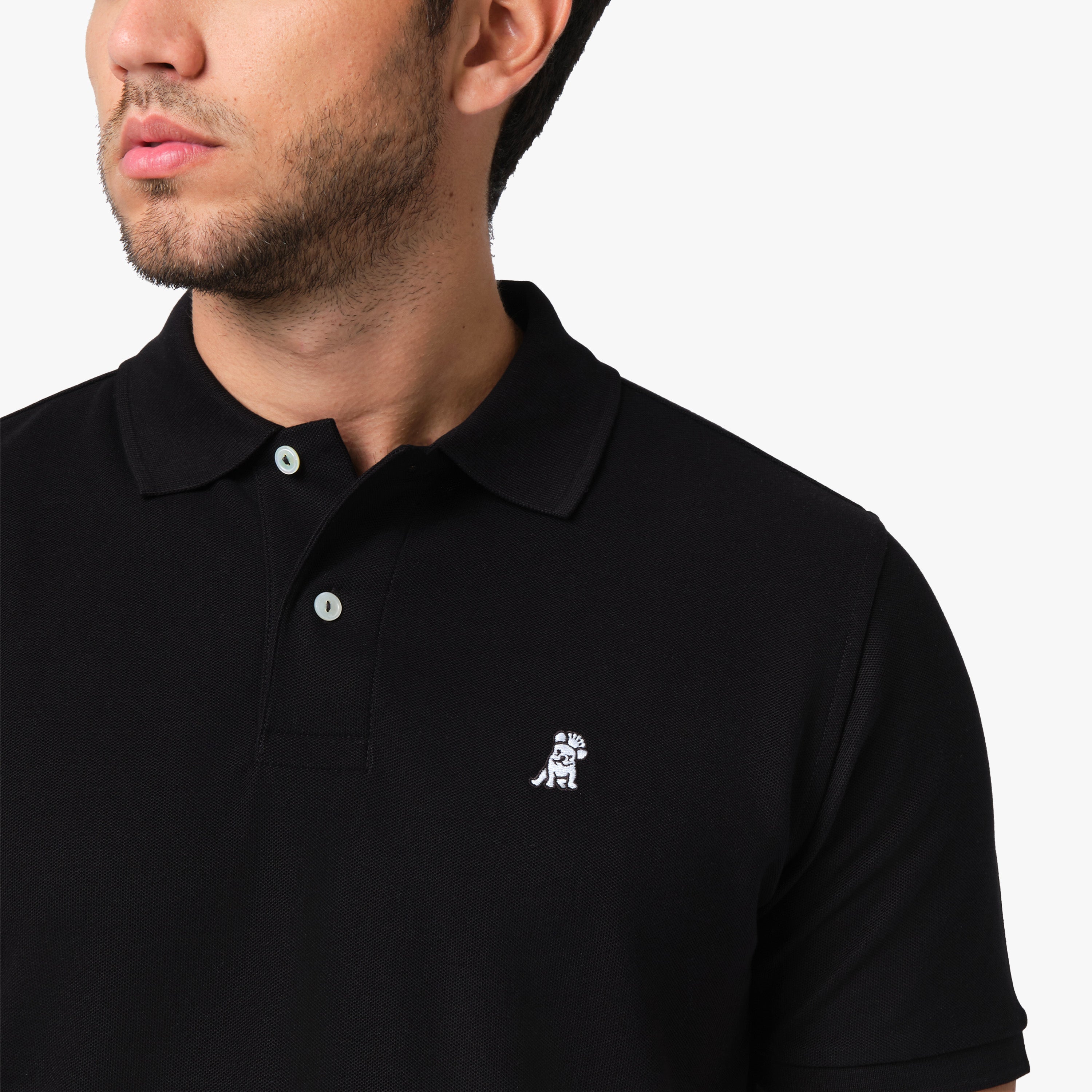 Close-up of a man wearing the black polo shirt, showing the collar and the small embroidered logo on the chest.