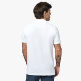 A rear view of a man wearing the white polo shirt and blue jeans.