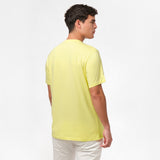 Back view of the man wearing the light yellow t-shirt, standing with his arms at his sides, paired with white shorts.