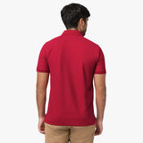 A rear view of a man wearing the red polo shirt and beige pants.