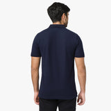 A rear view of a man wearing the navy blue polo shirt and black pants.
