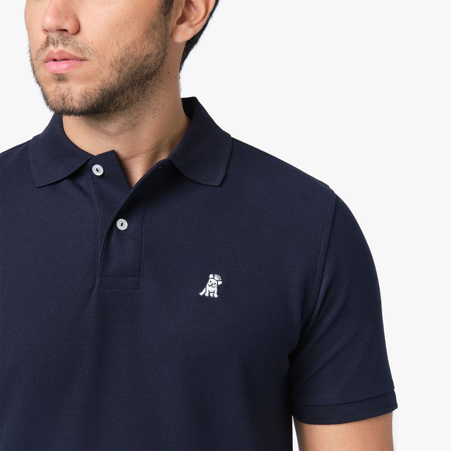 Close-up of a man wearing the navy blue polo shirt, showing the collar and the small embroidered logo on the chest.