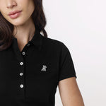 Close-up of the woman’s face and chest area, highlighting the collar and logo detail on the polo shirt.