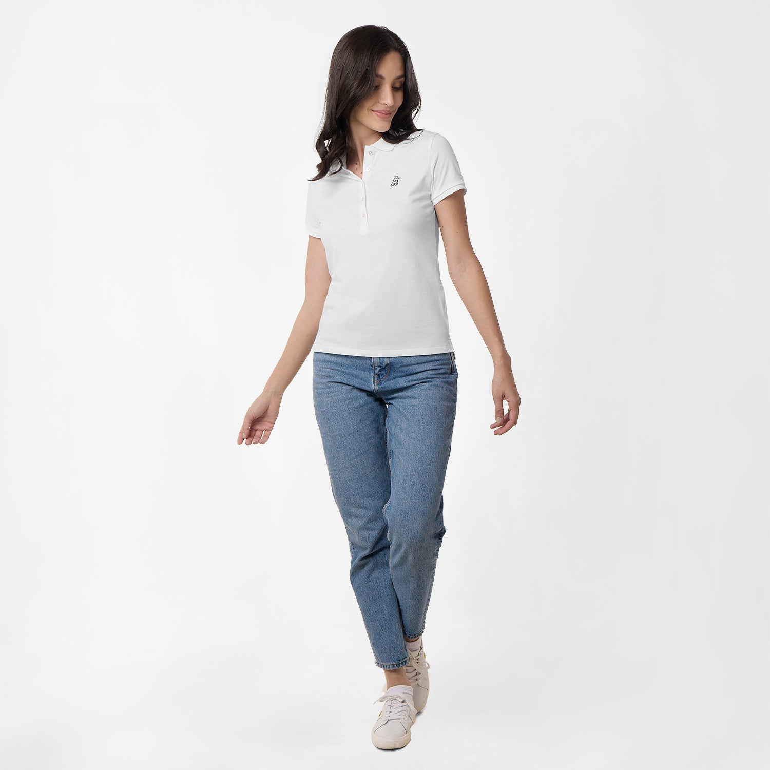 Full-body view of the woman wearing the white polo shirt and jeans, walking with one foot forward.