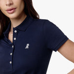  Close-up of the woman’s face and chest, highlighting the collar and white logo on the navy blue polo shirt.