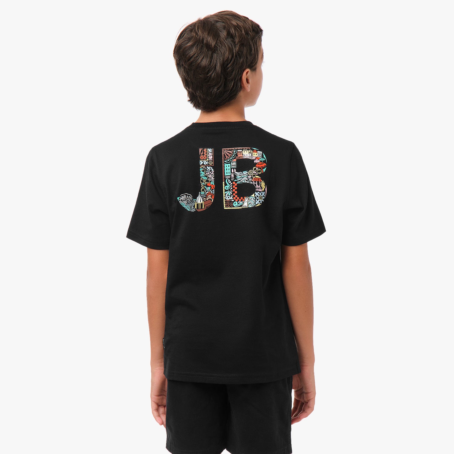 Rear view of a boy wearing a black t-shirt with large "JB" lettering on the back, filled with a colorful pattern.