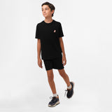 Boy walking while wearing the black t-shirt and black shorts, facing forward.