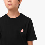 Close-up front view of a boy wearing the black t-shirt with a small embroidered logo on the chest.