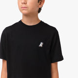 Close-up front view of a boy wearing the black t-shirt with a small embroidered logo on the chest.