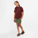 Full-body view of a girl wearing the maroon t-shirt and olive green shorts, standing with one hand on her hip.