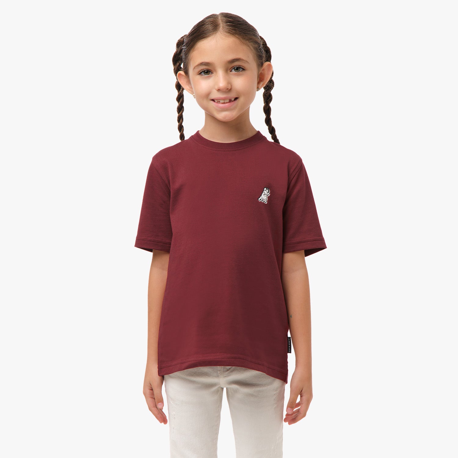 Front view of a girl standing and wearing a maroon t-shirt with a small logo on the chest.