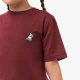  Close-up front view of a girl wearing the maroon t-shirt with a small embroidered logo on the chest.